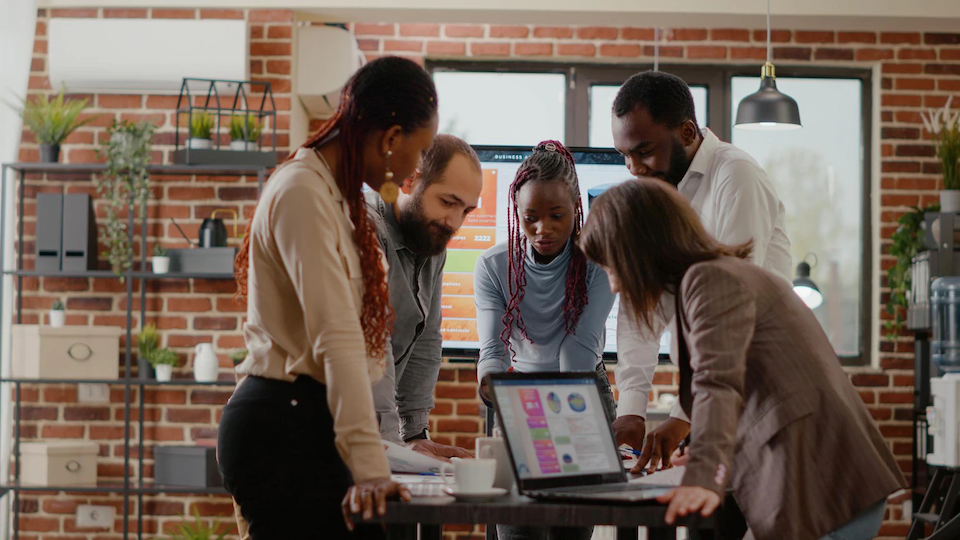 Group of diverse people looking at a laptop.png